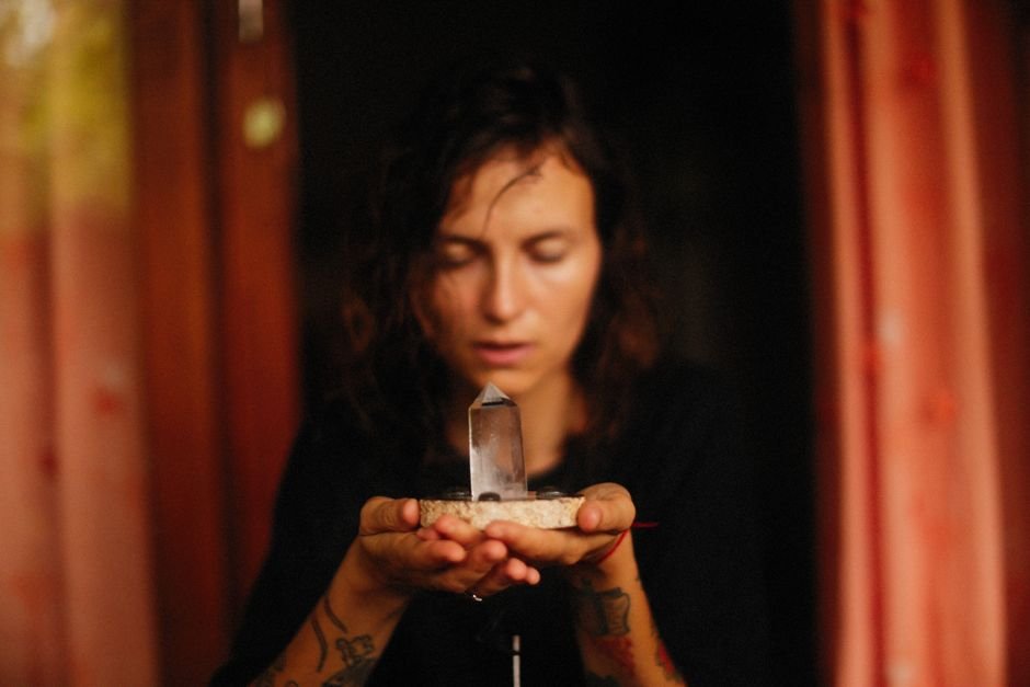 Woman meditating with a crystal held in her hands while setting a clear intention during a daily practice session
