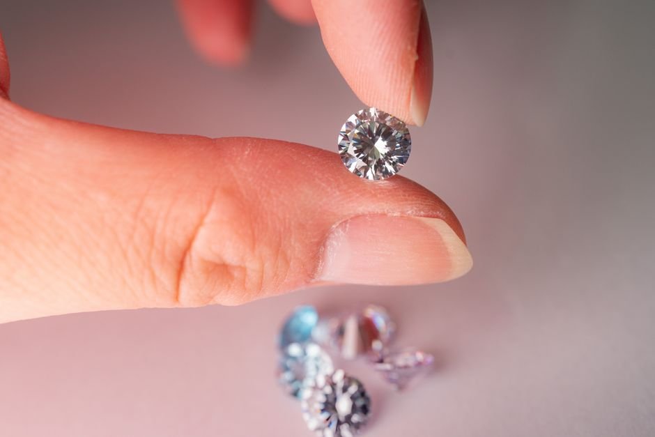 how to test a gemstone at home — fingers holding a faceted gem up close for inspection