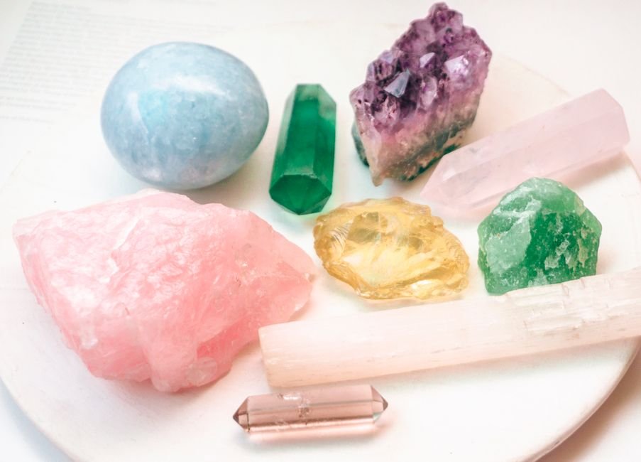 amethyst, rose quartz, citrine, and a selenite wand arranged on a white charging plate, showing how to recharge a crystal that feels dead