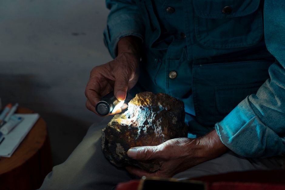 How to Check a Crystal for Cracks — Inspect Under Bright Light Hands using a small flashlight to closely inspect a rough stone for hairline cracks