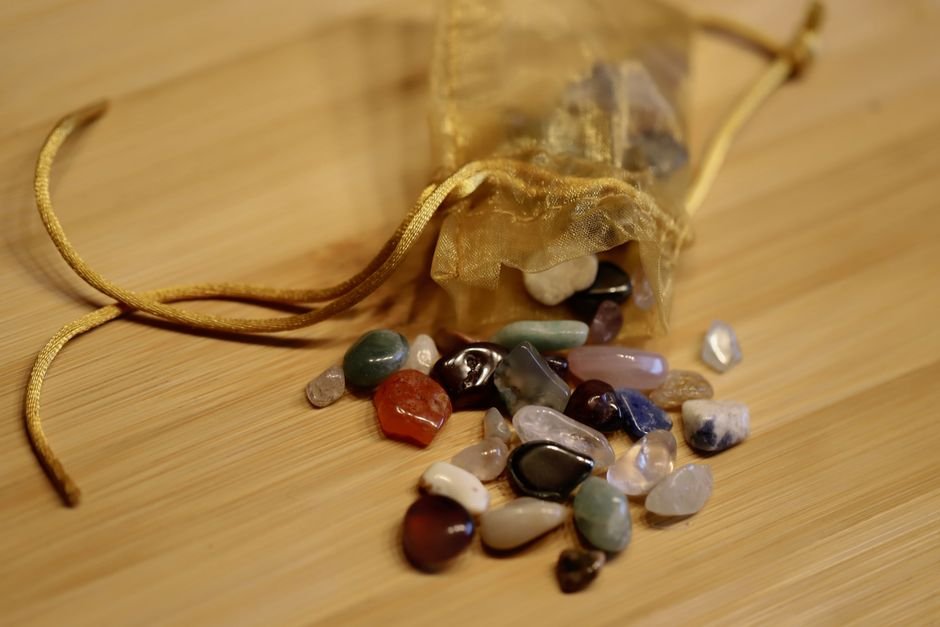 Crystal Storage Tips — Pouch and Padding Fixes That Stop Chipping Tumbled stones spilling from a sheer drawstring pouch onto wood, the loose mixed storage that causes mystery chips