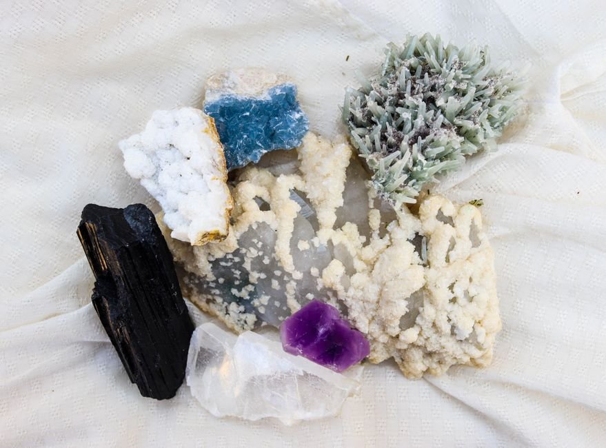 Gemstone Scratch Test Science — Every Mineral Has Measurable Properties Raw mineral specimens including black tourmaline, amethyst, and blue calcite, each with its own hardness and density
