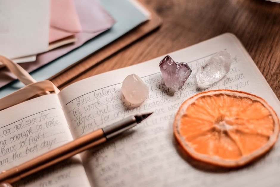 Open crystal journal with rose quartz, amethyst, and clear quartz resting on handwritten pages for daily tracking