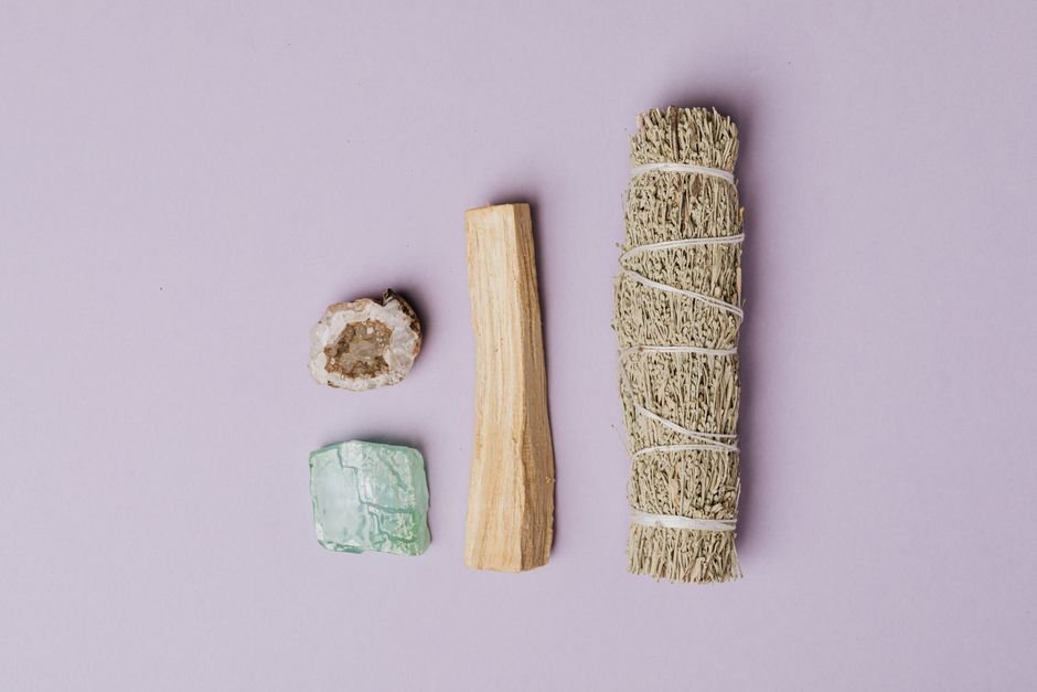 Fix Your Crystal Practice — Stone-Safe Cleansing and Intention Basics Quartz geode, green calcite, palo santo, and a sage bundle laid out for stone-safe crystal cleansing