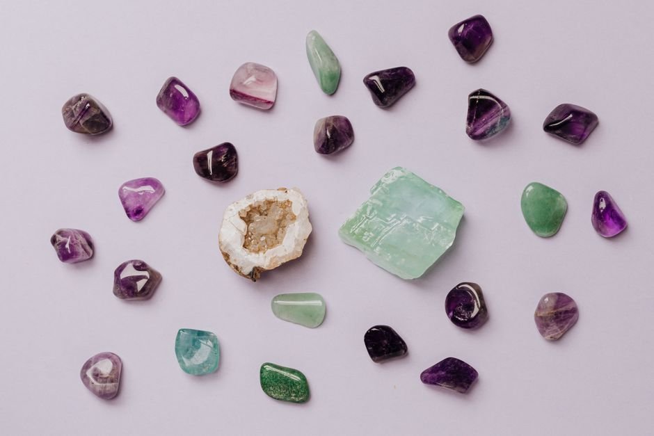 How to Use Crystals Correctly — Real Gem Durability, Not Ritual Rules Tumbled amethyst, fluorite, and calcite spread out separately on a light surface, stones with different hardness and sun sensitivity