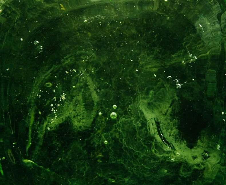 Moldavite Flow Texture vs Glass Bubbles — What to Look For Under a Loupe Green glass texture with swirls and round air bubbles, the factory-style bubbles that give away cast glass fakes