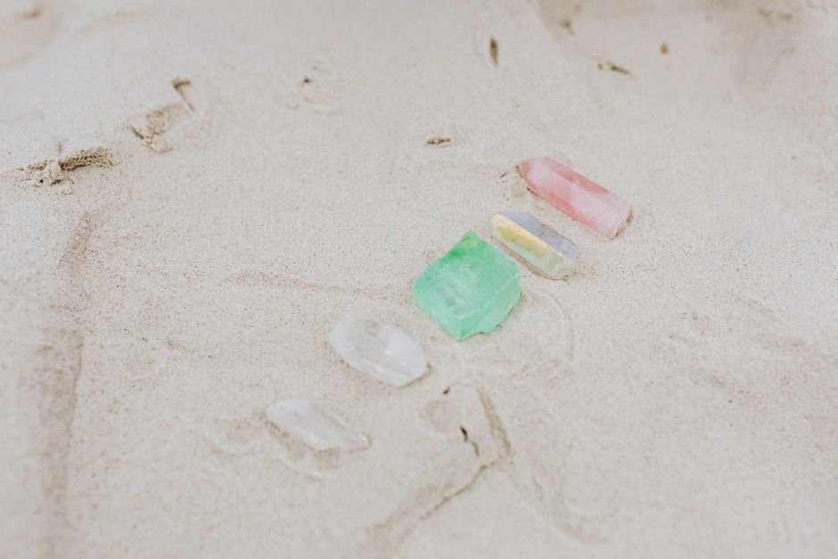 should I bury a broken crystal — rose quartz, fluorite, and clear quartz pieces resting on sand, returning to the earth