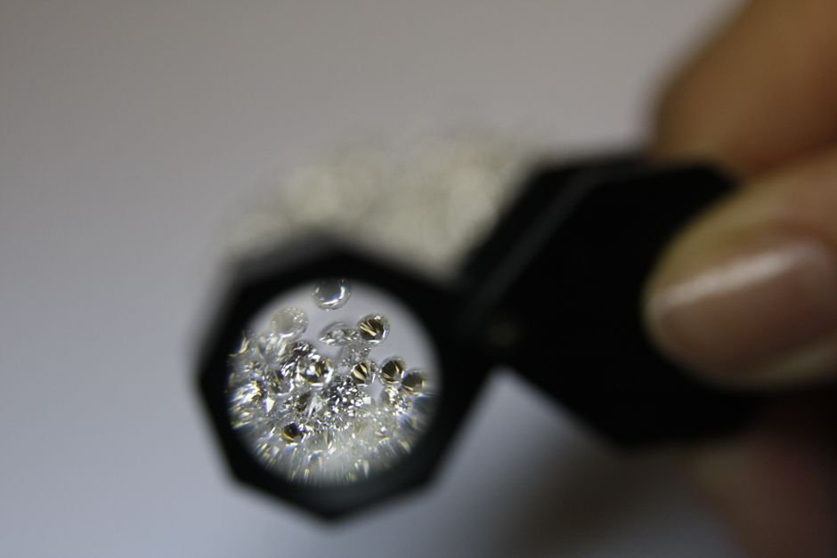 Jeweler's loupe magnifying small gemstones to check for the bubbles and inclusions that separate glass from quartz