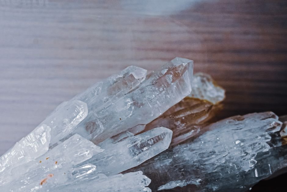 broken crystal pieces of clear quartz scattered on a wooden table, ready to be repurposed or buried