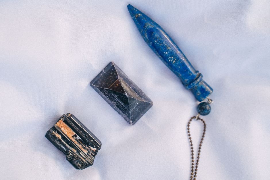Black tourmaline, amethyst pyramid, and lapis lazuli point laid out on white fabric for an intention-matched crystal test