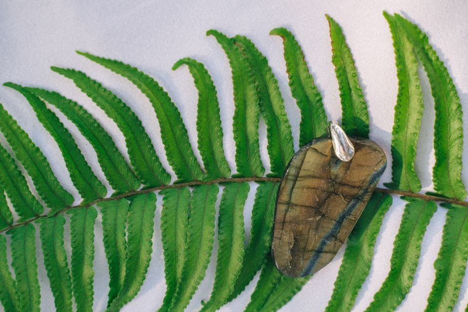 Cracked Labradorite Pendant Re-Cut — A Real Lapidary Repair Example Labradorite pendant resting on a green fern leaf, like the cracked pendant re-cut into a smaller cabochon