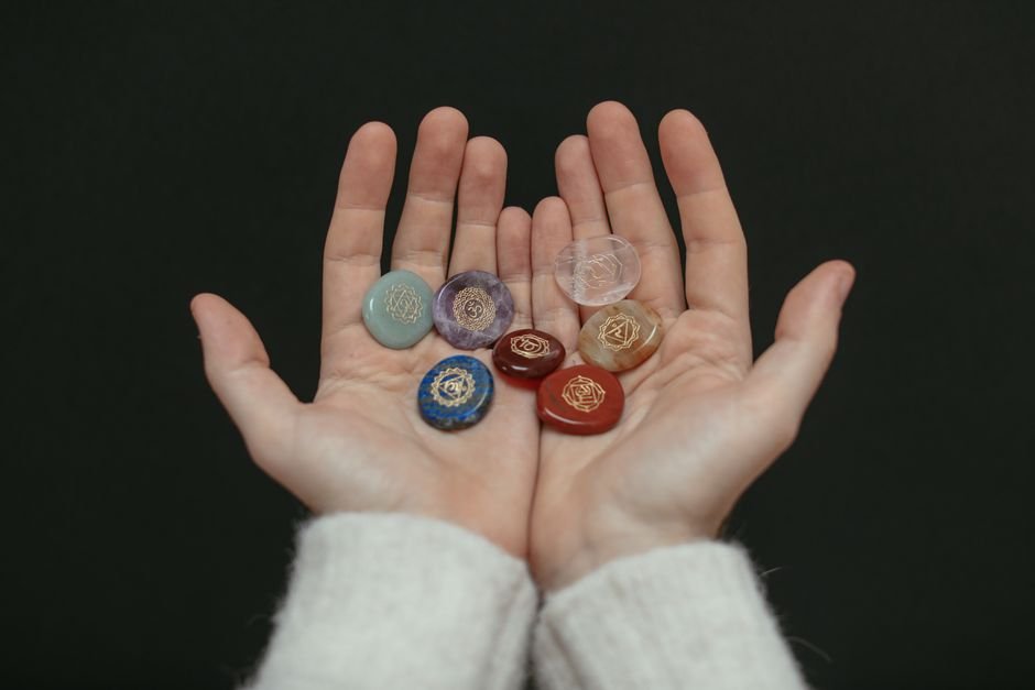 Open hands holding engraved chakra stones during an activation ritual, illustrating how do I know if my crystal is activated