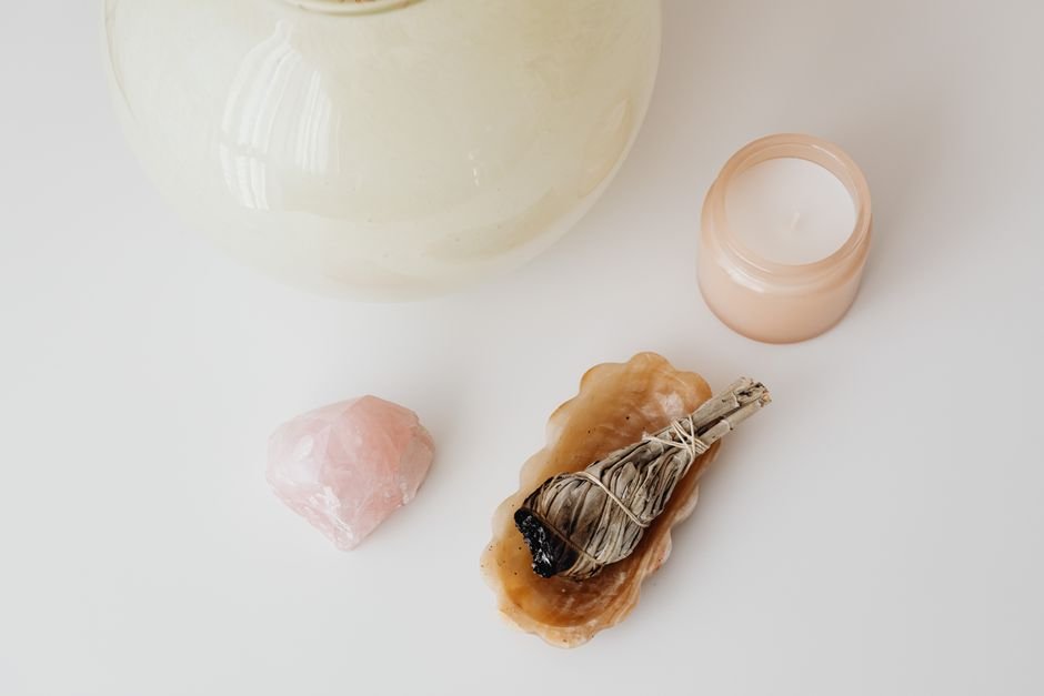Crystal Activation Ritual — Intention Setting With Rose Quartz and Palo Santo Rose quartz, a palo santo smudge stick, and a candle arranged for a crystal activation and intention-setting ritual