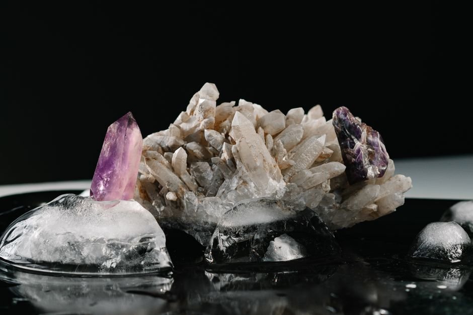 Crystal Energy Blockers — What Science Says About Quartz and Amethyst Amethyst points and a quartz cluster on melting ice against a black background, the minerals cited in crystal energy research