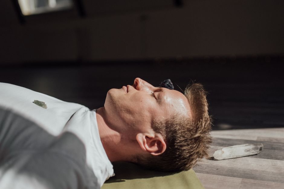 Man lying down meditating with a crystal placed on his forehead, mirroring the sessions used in crystal placebo research