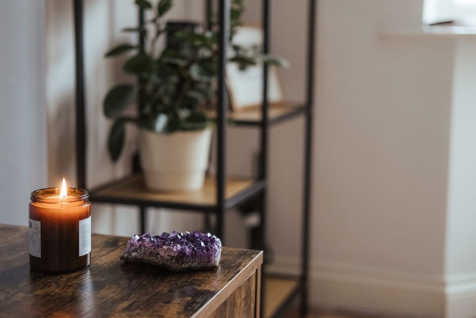 natural amethyst cluster on a wooden cabinet beside a burning candle, illustrating what blocks crystal energy