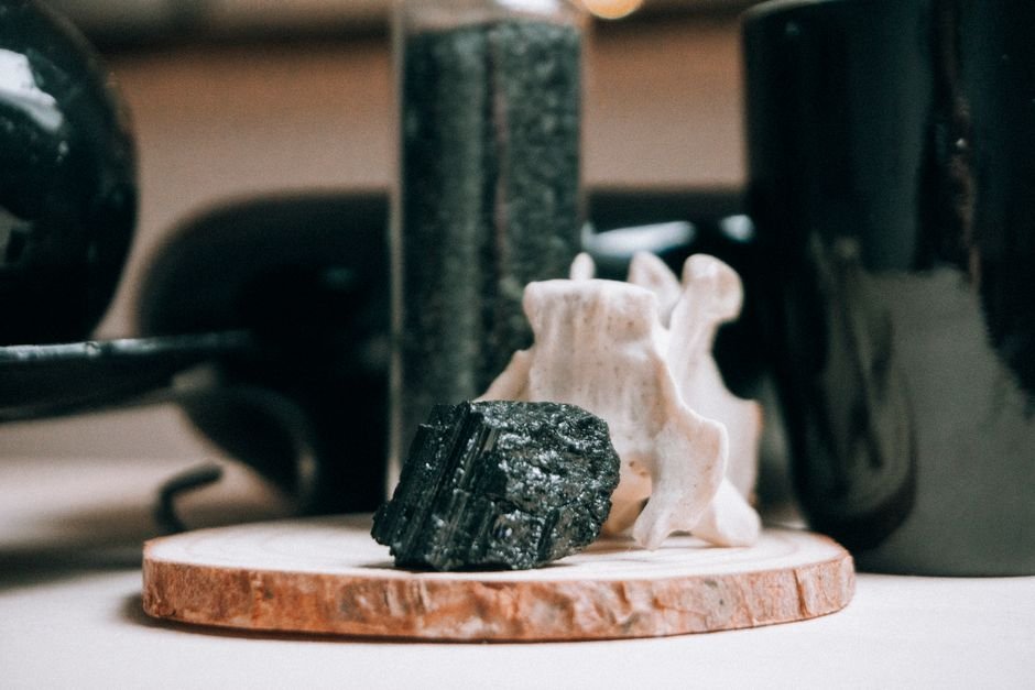 Rough black tourmaline stone on a wooden slab, the protective crystal practitioners say cracks after absorbing a hit