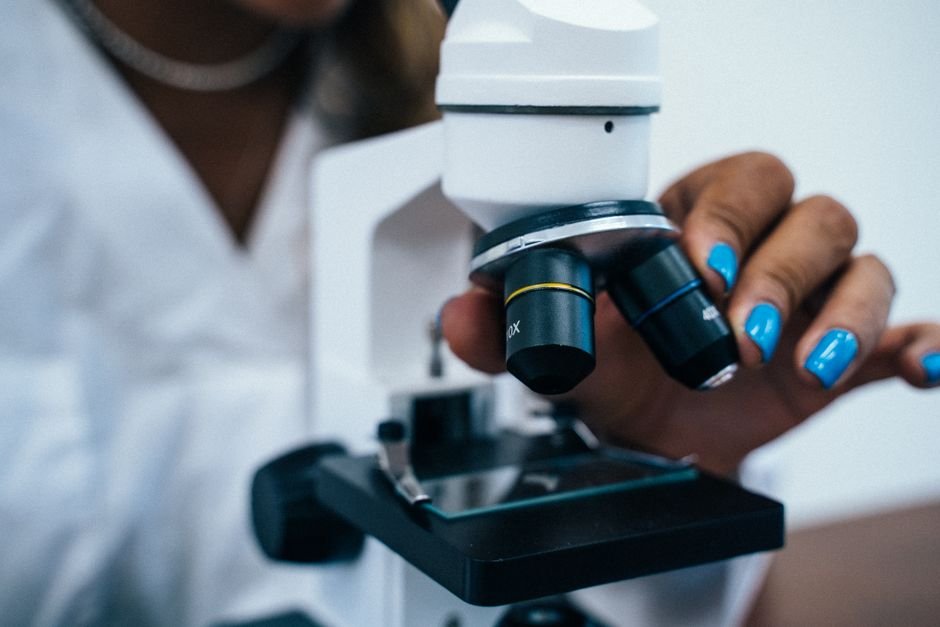 Scientist's hand adjusting a microscope, the instrument-based testing that confirms what a glance can't
