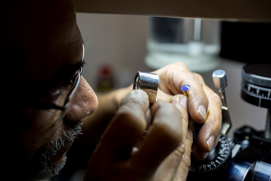 can broken crystals be repaired — jeweler examining a damaged gemstone through a loupe