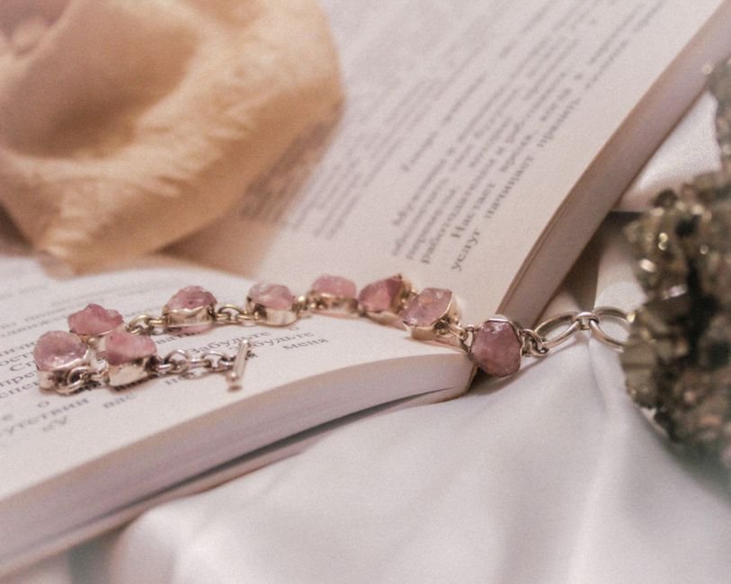 Pink crystal bead bracelet resting on an open book, the kind of piece that dulls fastest from daily wear