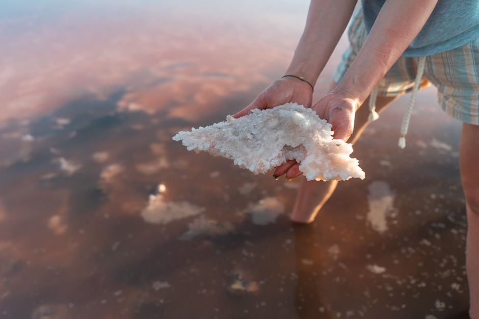 Hands holding rough salt crystals from a saline lake, halite being the most water-sensitive stone of all