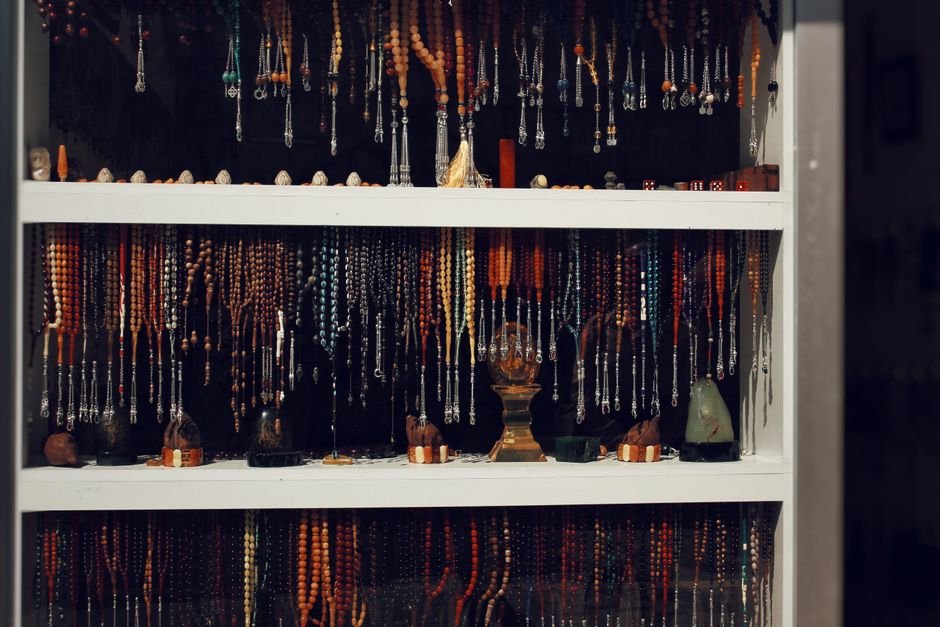 Assorted beaded jewellery displayed in a shop window, where dyed and natural material sit side by side