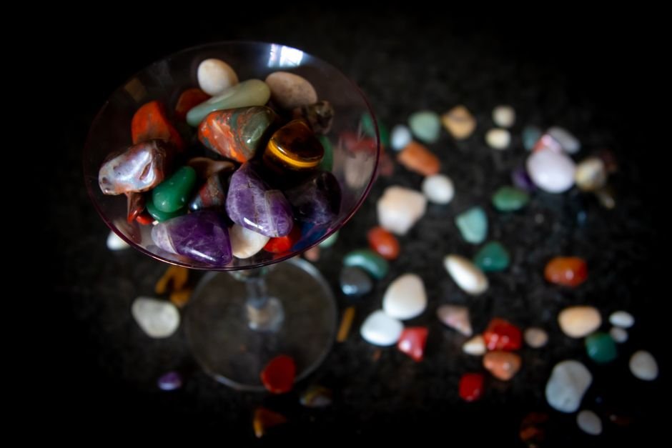 Polished stones stored loose together in a glass, the kind of storage that dulls a crystal's surface through constant contact