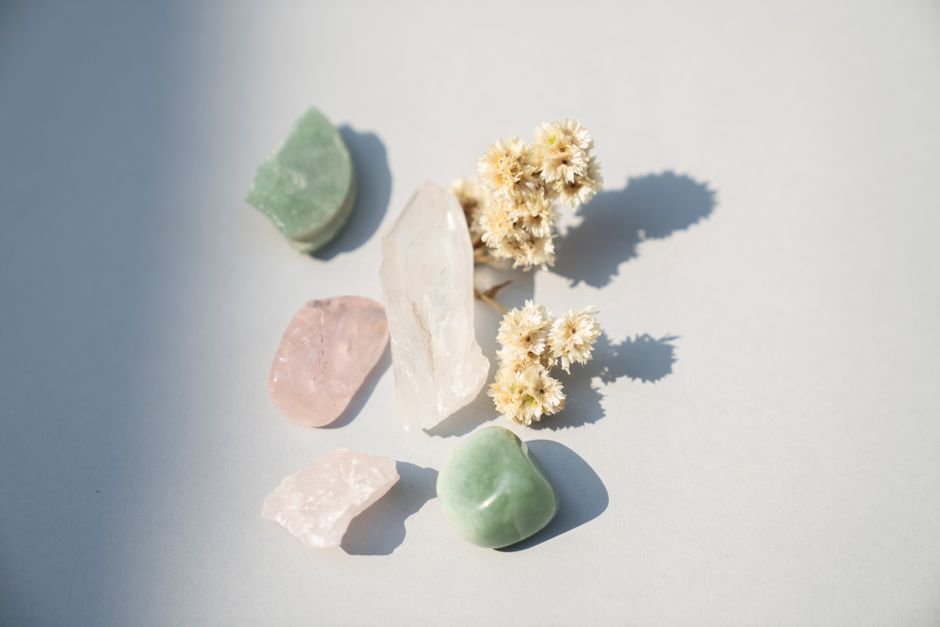 Healing crystals and dried flowers indoors casting hard shadows in direct sunlight coming through a window