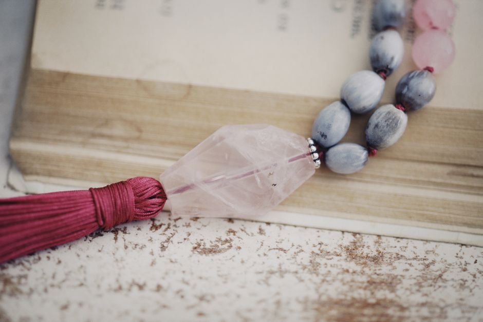 Rose quartz beaded necklace resting on a book, the kind of piece that pales where it rubs